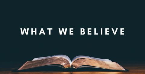 "What We Believe" over an open Bible resting on a wooden table